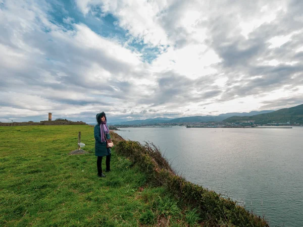 Paltolu bir kadın uzaktaki Bilbao limanına ve denize bakıyor..