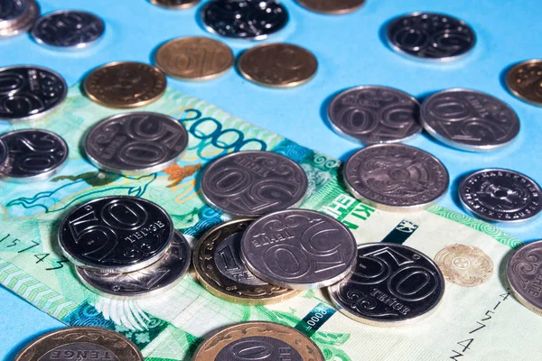 Tenge sobre un fondo azul con monedas. Billetes de Tenge. Monedas de —  Fotos de Stock