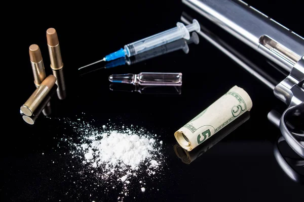 A syringe with ampoules, white powder, a five-dollar bill with bullets and a gun lying on a black glass background.  Dangerous bad habits, addiction to drugs and gambling. Crime because of drugs. — Stock Photo, Image
