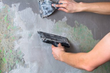 İnşaat karışımı ve pürüzsüz bir spatula tutan bir el.