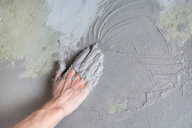 Sıva ustası alçıyı eliyle duvara yapıştırıyor.