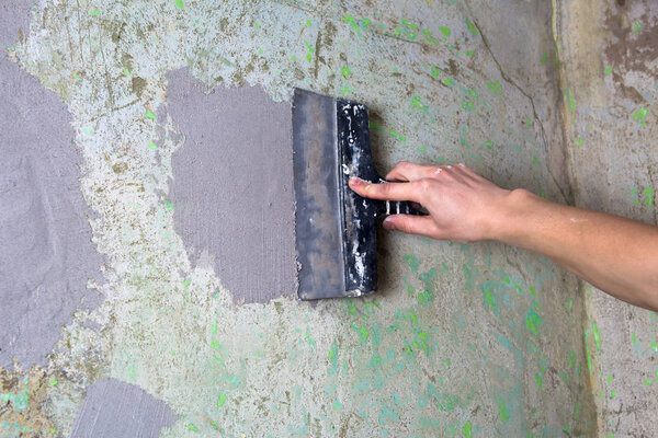 The Builder puts plaster on the wall.Hand holding a spatula with