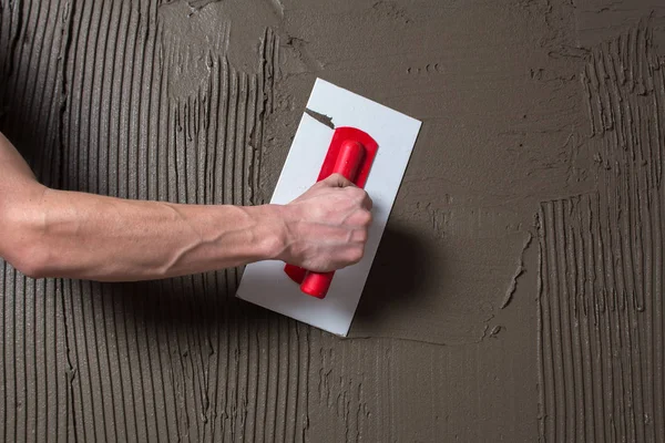 Hand hält einen Spachtel mit Baumischung und glättet. — Stockfoto