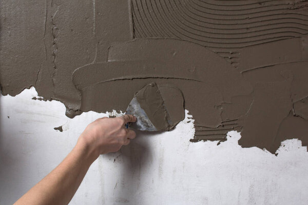 Почини стену. Оштукатуривание обоев. Рука держит лопатку с
