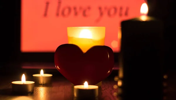 Um coração vermelho está contra um fundo de velas acesas e t — Fotografia de Stock