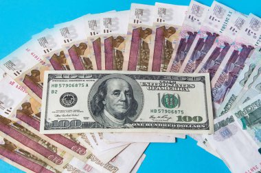 Rus rublesinin kağıt banknotları ve Rus rublesi üzerine 100 dolar. Rubleler Rusya 'nın ulusal para birimidir. Rus bankası. Mavi bir arkaplanda Rus rublesi. Rubledeki büyüme.