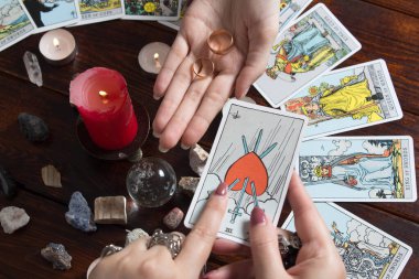 Bangkok, Tayland, 15.20 Mart. Kız elinde Tarot kartları, kristaller, sihirli bir top ve yanan bir mumla evlilik yüzükleri tutuyor. Aşk için fal bakımı, aşk büyüsü..