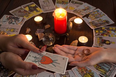 Bangkok, Tayland, 15.20. Kız elinde Tarot kartları, kristaller, sihirli bir top ve yanan bir mum ile evlilik yüzükleri tutuyor. Aşk için fal bakımı, aşk büyüsü.