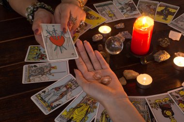 Bangkok, Tayland, 15.20. Kız elinde Tarot kartları, kristaller, sihirli bir top ve yanan bir mum ile evlilik yüzükleri tutuyor. Aşk için fal bakımı, aşk büyüsü.