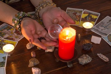 Bangkok, Tayland, 15.20 Mart. Kız elinde Tarot kartları, kristaller, sihirli bir top ve yanan bir mumla evlilik yüzükleri tutuyor. Aşk için fal bakımı, aşk büyüsü..