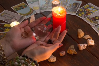 Bangkok, Tayland, 15.20 Mart. Kız elinde Tarot kartları, kristaller, sihirli bir top ve yanan bir mumla evlilik yüzükleri tutuyor. Aşk için fal bakımı, aşk büyüsü..