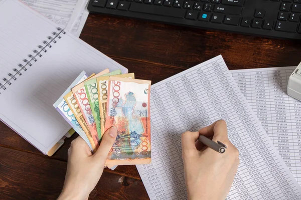 Tenge KZT banknotları bilgisayarın, not defterinin ve belgelerin yanında. Kağıt banknotlar KZT 'yi gerer. Kazakistan Bankası
