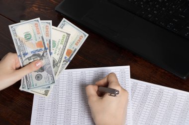 Ofiste finansla çalış. Bir kasiyer ofis çalışma alanının üzerinde dolar tutar. Belgeler, yazar kasa, bir telefon ve bir bilgisayar. Şirketteki maaş ve borçların ödenmesi zorunluluğu.