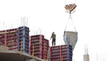 Yeni bina ve binaların onarımı ve inşaatı. İnşaat mühendisi inşaat halindeki çok katlı binanın duvarlarını inşaat vinci kullanarak somutlaştırıyor ve sürücüye el hareketlerini gösteriyor..