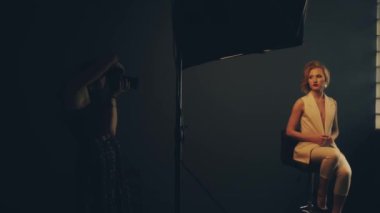 Stüdyoda bir kadın fotoğraf mankeni çekiyor.