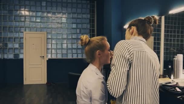 Профессиональный визажист накладывает косметику на лицо блондинки — стоковое видео