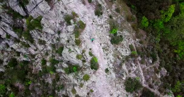 Foto aérea de un ciclista de montaña levantando su bicicleta en la cima de la montaña. — Vídeos de Stock