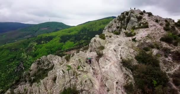 Tiro aéreo de um motociclista de montanha levantando sua bicicleta no topo da montanha. — Vídeo de Stock