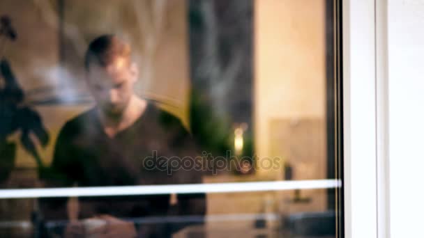 Schöner Mann in seinem Haus hinter dem Fenster — Stockvideo