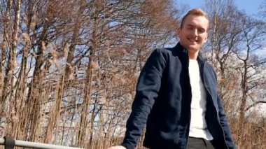 Gülümseyen adam açık havada oturuyor