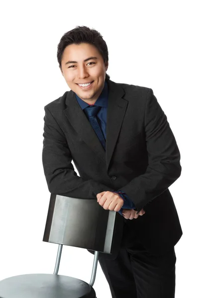 Smiling businessman leaning towards a chair — Stock Photo, Image