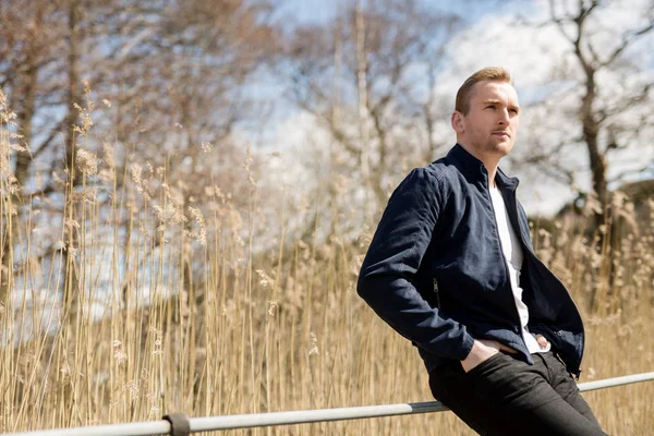 Man in zijn 20s met tarweveld achter hem gericht — Stockfoto