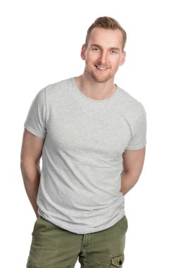 Gülümseyerek, beyaz bir arka plan karşı kapalı duran gri tişörtlü yakışıklı adam.