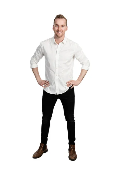 英俊的男子站在白色背景的前面身穿白色衬衫和黑色牛仔裤看着相机 — 图库照片