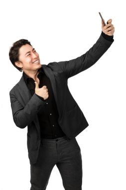 Bir selfie ile telefonunu alarak ve başparmak yaparken mutlu adam gülümsüyor. Beyaz arka plan.