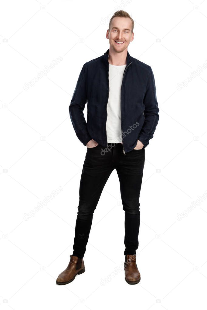 Blonde trendy man wearing a fashionable blue leather jacket, standing against a white background feeling great with a smile on his face. 
