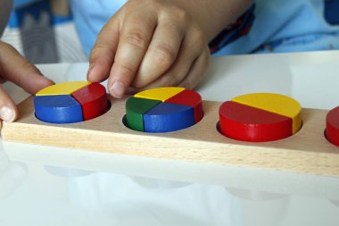 Çocuk Montessori ile oynuyor ve matematik öğreniyor. Kesirler için Montessori malzemesi. Anaokulunda öğreniyorum..