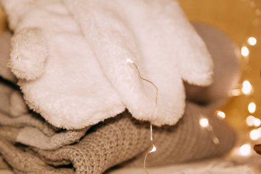 Yığın rahat örme kazak ve ahşap arka plan ışıkları garland. Sonbahar-Kış konsepti. Büyü, rahat ve ruh zaman