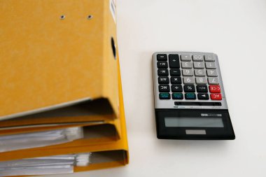 Hesap makinesi ile modern beyaz Resepsiyon masasında iş rapor kağıt dosya yığını.