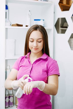 Balmumu ve şeker ustası birçok müşteri için harika bir işe hazır olduğunu gösteriyor. Kız ellerini dezenfekte ediyor.