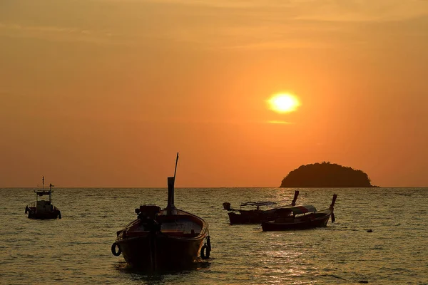 Bir tekne bir kızıl gökyüzü ve tropikal günbatımı karşı silüeti