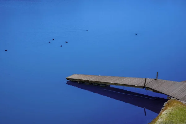Pasarela de madera al lago con agua azul — Foto de Stock