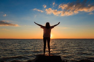 Kadın kendini uzatır ve gün batımını izler.