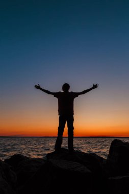 Taşın üzerinde kalan bir adamın silüeti. Akşamları