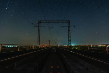 Gezgin yıldızların altında iki demiryolu arasında oturuyor.