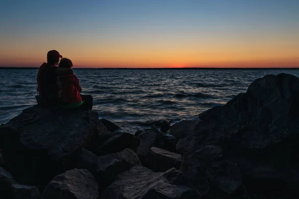 Casal sentado nas pedras e abraçando uns aos outros — Fotografia de Stock