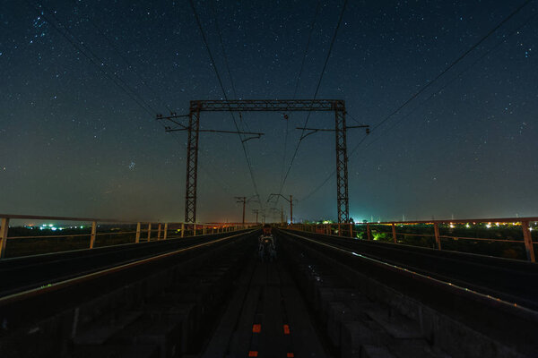 Странник, сидящий между двумя железными дорогами под звездами
