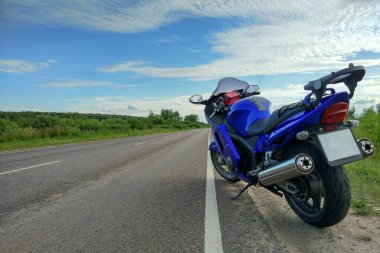 Orman bir asfalt yolda motosiklet binme sürücü.