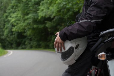 Orman bir asfalt yolda motosiklet binme sürücü.