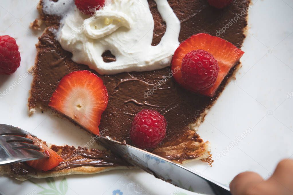 Raspberries and strawberries on a pancake with Nutella and whipped cream. 