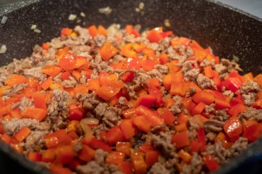 Kızartma tavasında çiğ et, soğan ve biber.