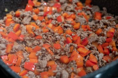 Kızartma tavasında çiğ et, soğan ve biber.