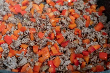 Kızartma tavasında çiğ et, soğan ve biber.