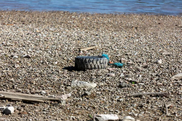 Old car tires on the river, Water and sea coast pollution car tires on sand beach