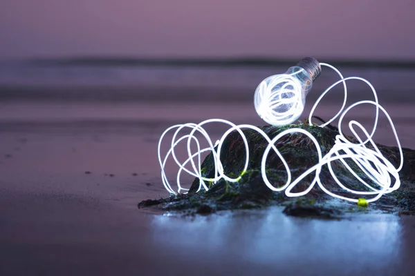 SMART BULB AT THE BEACH. CONCEPT: NEW TECHNOLOGY WITH ENVIRONMENT