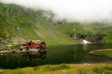 Sibiu County 'deki Chalet ve Glacier Gölü sisli ve yansımalı.